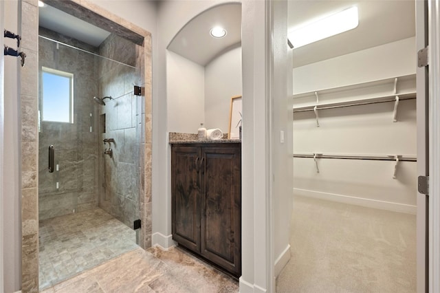 bathroom featuring a shower with door and vanity