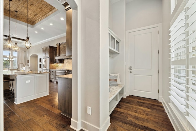 interior space featuring dark brown cabinetry, hanging light fixtures, a center island with sink, a kitchen breakfast bar, and dark hardwood / wood-style flooring