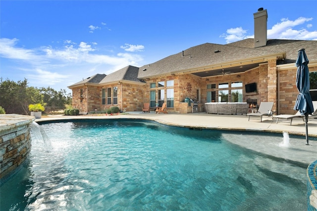 view of pool with pool water feature, a fireplace, and a patio area