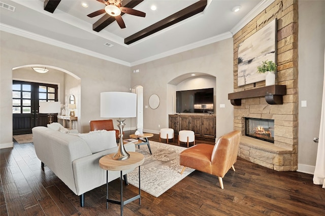 living room with dark wood-type flooring, crown molding, a raised ceiling, ceiling fan, and a fireplace