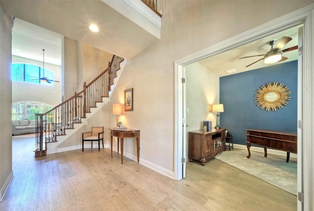 interior space with stairs, wood finished floors, a ceiling fan, and baseboards