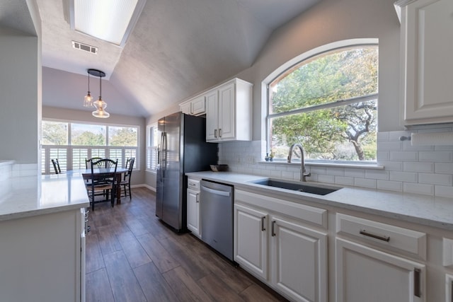 kitchen with decorative light fixtures, sink, white cabinets, light stone counters, and stainless steel appliances