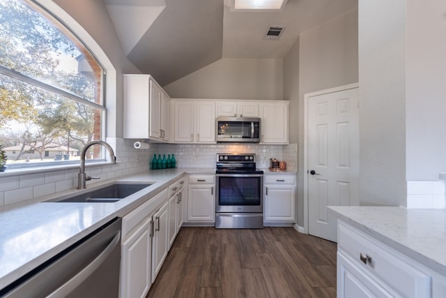 kitchen with sink, dark hardwood / wood-style floors, white cabinets, stainless steel appliances, and backsplash