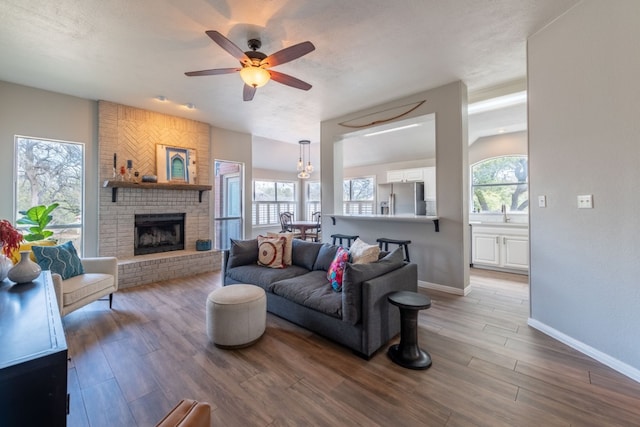 living room featuring a wealth of natural light, a brick fireplace, hardwood / wood-style floors, and ceiling fan