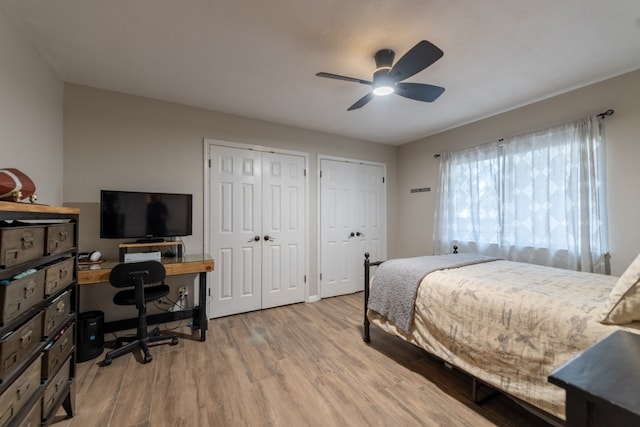 bedroom featuring multiple closets, ceiling fan, and light hardwood / wood-style flooring