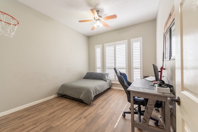 bedroom featuring ceiling fan, a textured ceiling, and light hardwood / wood-style floors