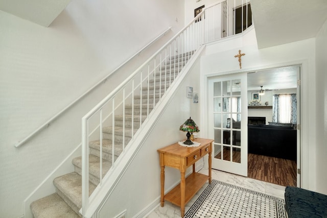 staircase with a towering ceiling and a fireplace