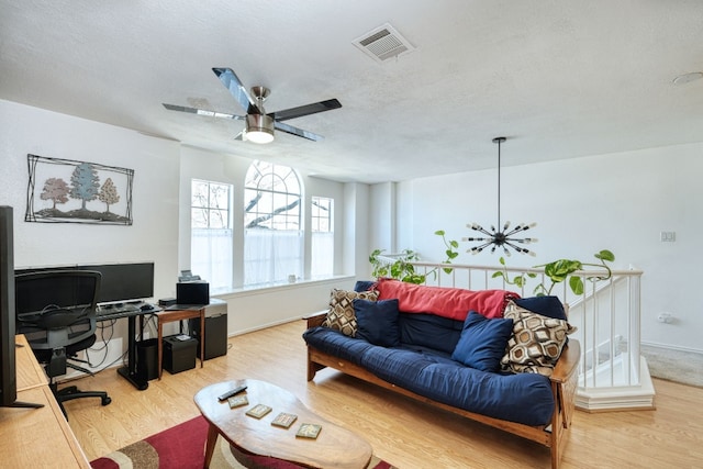 office with ceiling fan with notable chandelier, light hardwood / wood-style floors, and a textured ceiling