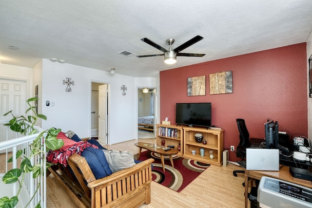 living room with ceiling fan, wood-type flooring, and a textured ceiling