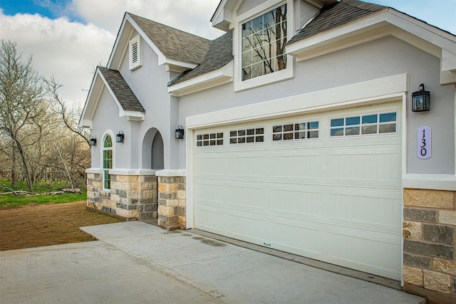 130 E Keomuku Ln, Bastrop, TX 78602 - view of front of house with driveway, stucco siding, a shingled roof, stone siding, and an attached garage