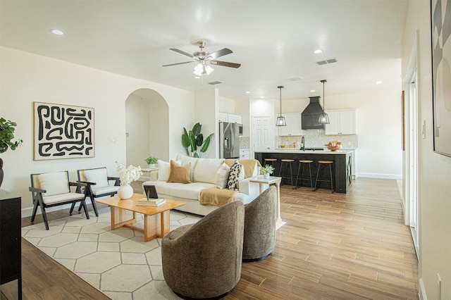 living room featuring sink, light hardwood / wood-style flooring, and ceiling fan