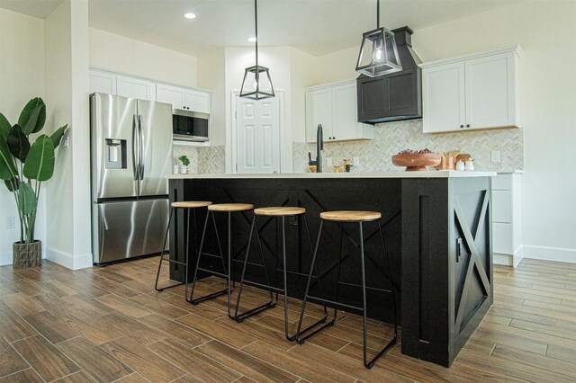 kitchen with stainless steel appliances, a kitchen bar, and white cabinets