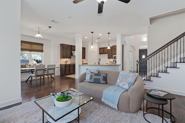 living room with dark wood-type flooring, ceiling fan, and sink