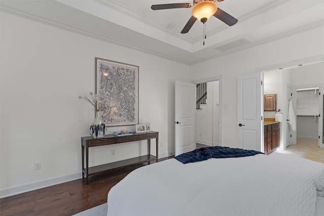 bedroom featuring crown molding, ensuite bath, ceiling fan, dark hardwood / wood-style flooring, and a raised ceiling