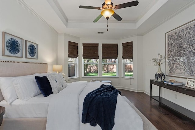 bedroom with dark wood-type flooring, ceiling fan, ornamental molding, and a raised ceiling