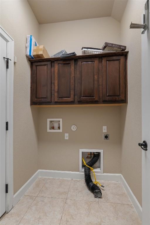 clothes washing area featuring light tile patterned flooring, cabinets, washer hookup, hookup for an electric dryer, and hookup for a gas dryer