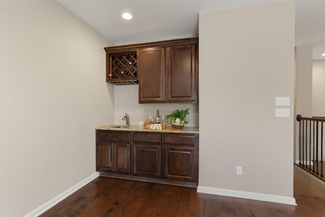 bar with dark hardwood / wood-style flooring, sink, and dark brown cabinets