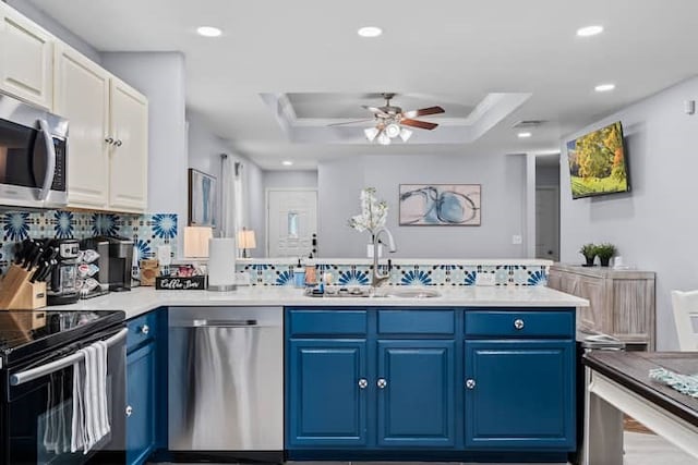 kitchen featuring a raised ceiling, white cabinetry, sink, stainless steel appliances, and blue cabinetry