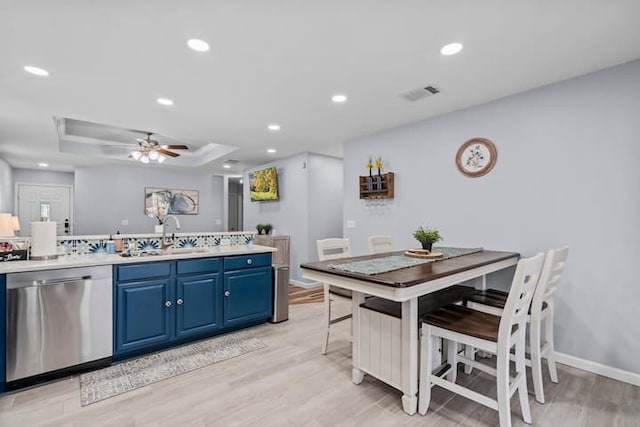 kitchen with blue cabinets, a kitchen bar, sink, stainless steel dishwasher, and light hardwood / wood-style floors