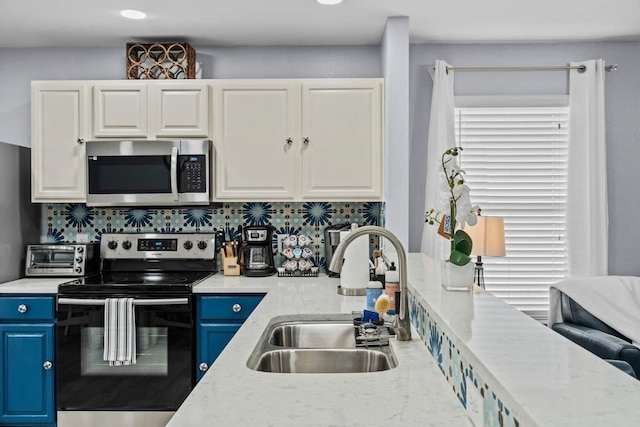 kitchen with blue cabinetry, stainless steel appliances, sink, and tasteful backsplash