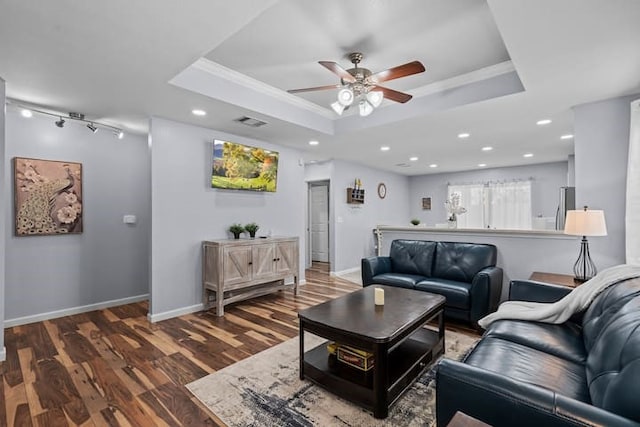 living room with a tray ceiling, ornamental molding, dark hardwood / wood-style floors, and ceiling fan