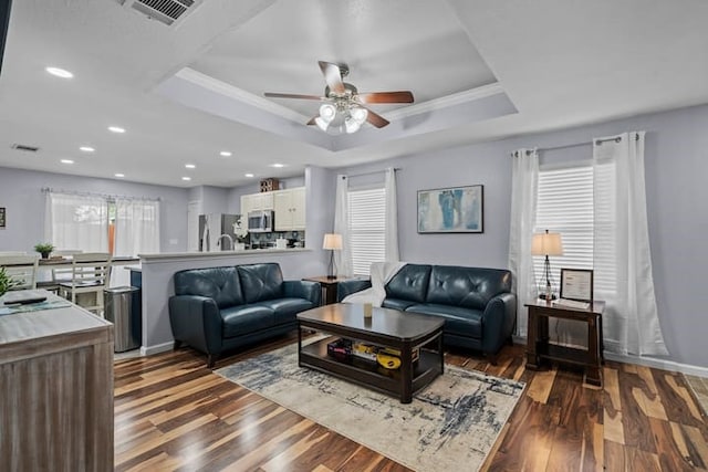 living room featuring hardwood / wood-style floors, ornamental molding, a raised ceiling, and ceiling fan