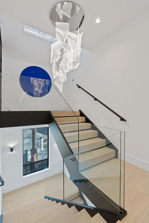 stairs featuring hardwood / wood-style flooring and an inviting chandelier