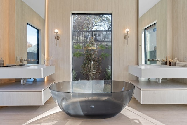 bathroom with vanity, a bath, and wood-type flooring