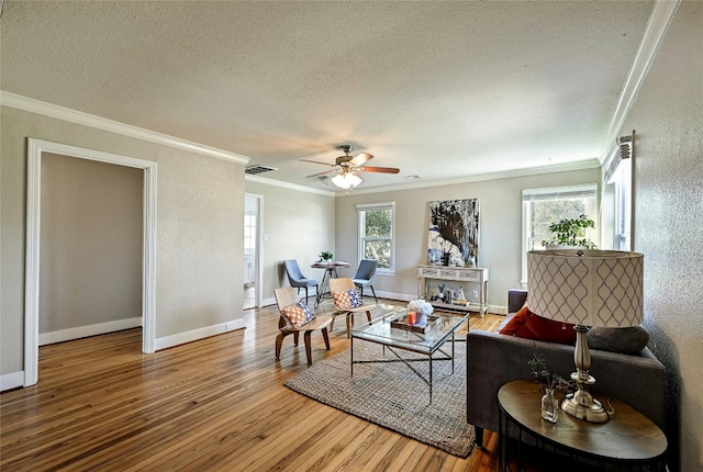 living room featuring ceiling fan, crown molding, wood-type flooring, and a textured ceiling