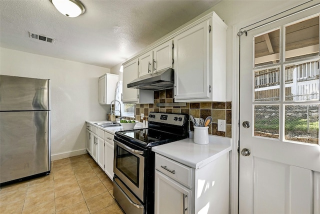 kitchen featuring sink, white cabinetry, light tile patterned floors, stainless steel appliances, and backsplash