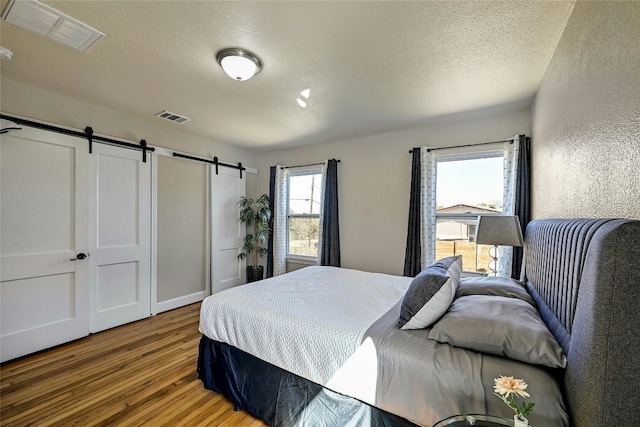 2201 Indian Creek Rd, Austin, TX 78734 - bedroom with wood finished floors, a barn door, a textured ceiling, and a textured wall