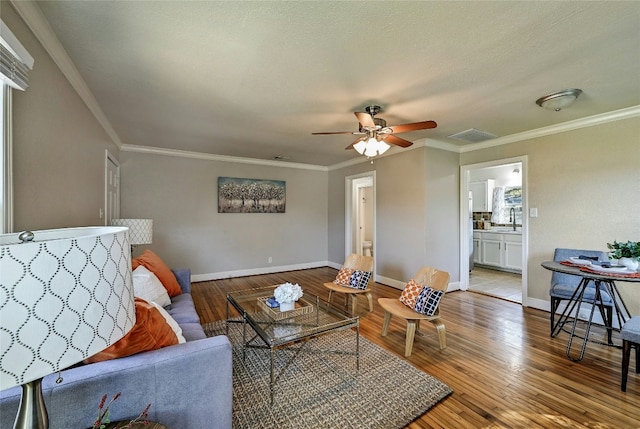 living room with ornamental molding, sink, light hardwood / wood-style floors, and a textured ceiling