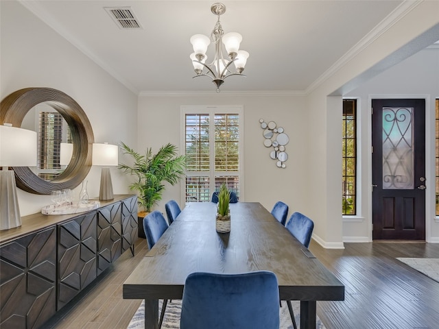 dining area with wood-type flooring, an inviting chandelier, and crown molding