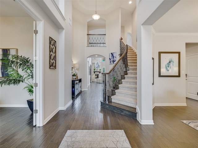 foyer entrance featuring dark wood-type flooring, crown molding, and a high ceiling