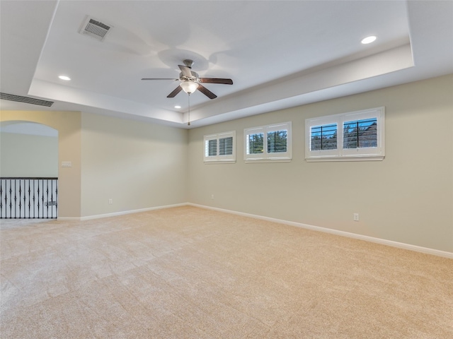 carpeted empty room with ceiling fan and a tray ceiling