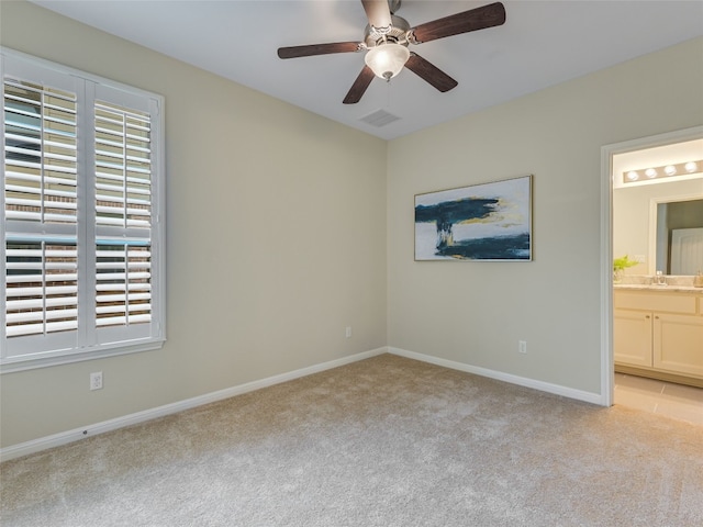 unfurnished bedroom featuring multiple windows, ensuite bath, sink, and light carpet