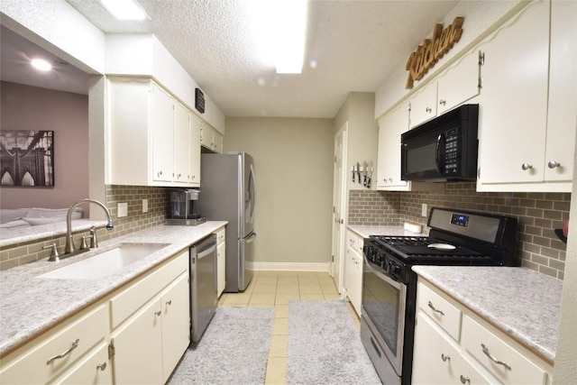 kitchen featuring sink, white cabinetry, a textured ceiling, light tile patterned floors, and stainless steel appliances