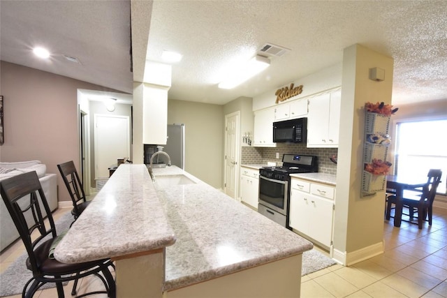 kitchen with sink, appliances with stainless steel finishes, kitchen peninsula, decorative backsplash, and white cabinets