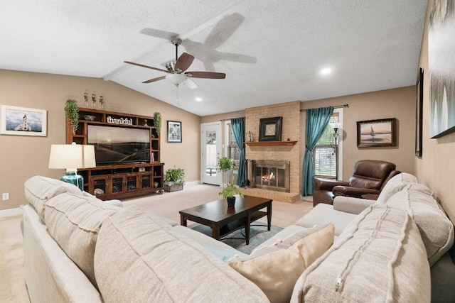 living room with ceiling fan, vaulted ceiling with beams, a fireplace, a textured ceiling, and light colored carpet