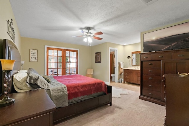 carpeted bedroom with french doors, ceiling fan, connected bathroom, and a textured ceiling