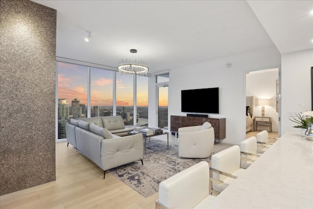 living room featuring floor to ceiling windows, an inviting chandelier, and light hardwood / wood-style flooring