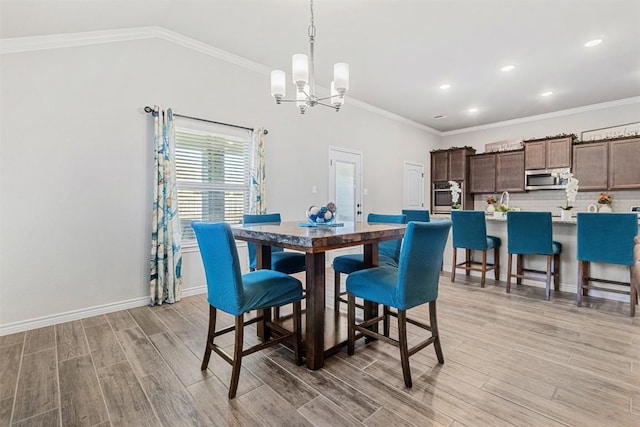 dining space featuring crown molding, vaulted ceiling, and light hardwood / wood-style floors