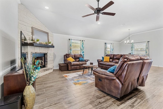 living room with a stone fireplace, wood-type flooring, vaulted ceiling, ornamental molding, and ceiling fan with notable chandelier