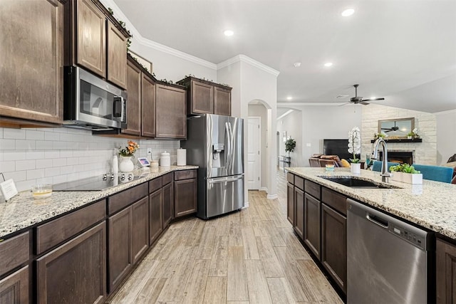 2651 Cowgirl Trl, Belton, TX 76513 - kitchen with stainless steel appliances, a sink, ceiling fan, dark brown cabinetry, and a fireplace