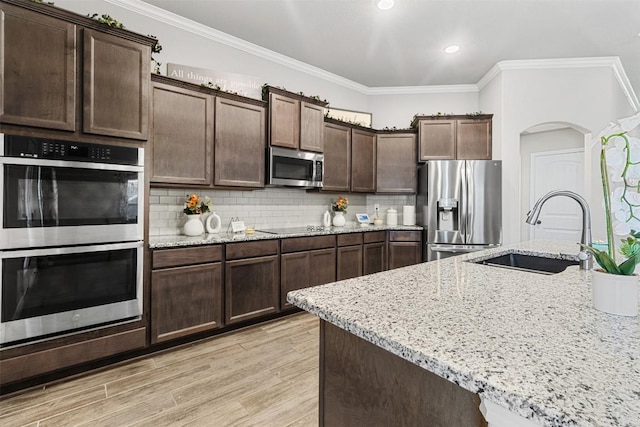 2651 Cowgirl Trl, Belton, TX 76513 - kitchen with appliances with stainless steel finishes, a sink, ornamental molding, arched walkways, and dark brown cabinets
