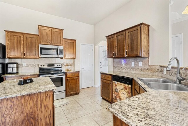 kitchen with light tile patterned flooring, appliances with stainless steel finishes, sink, and light stone counters