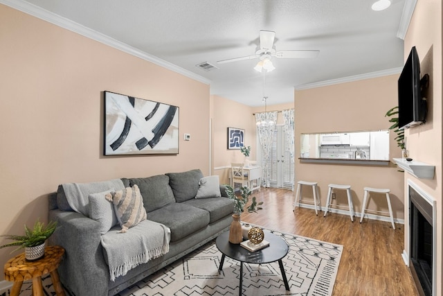 living room with crown molding, hardwood / wood-style flooring, and ceiling fan with notable chandelier