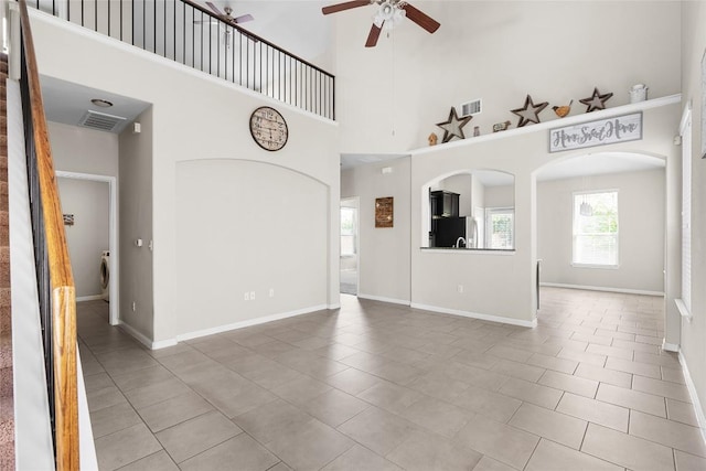 unfurnished living room with tile patterned flooring, a high ceiling, and ceiling fan