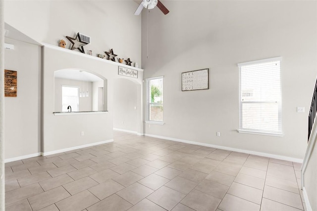 tiled empty room featuring a towering ceiling and ceiling fan