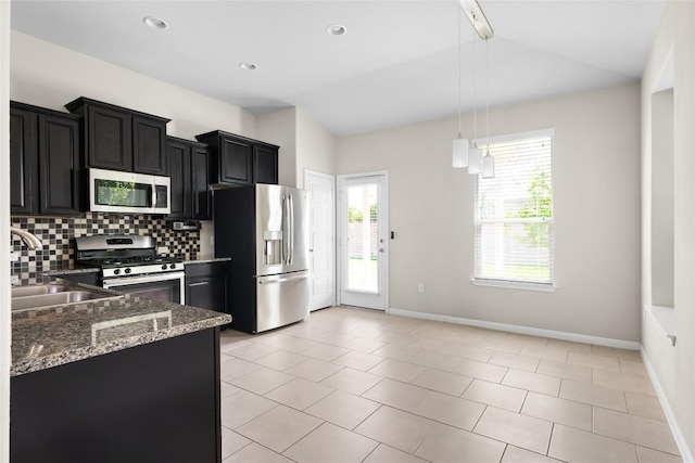 kitchen with sink, decorative light fixtures, dark stone countertops, appliances with stainless steel finishes, and decorative backsplash